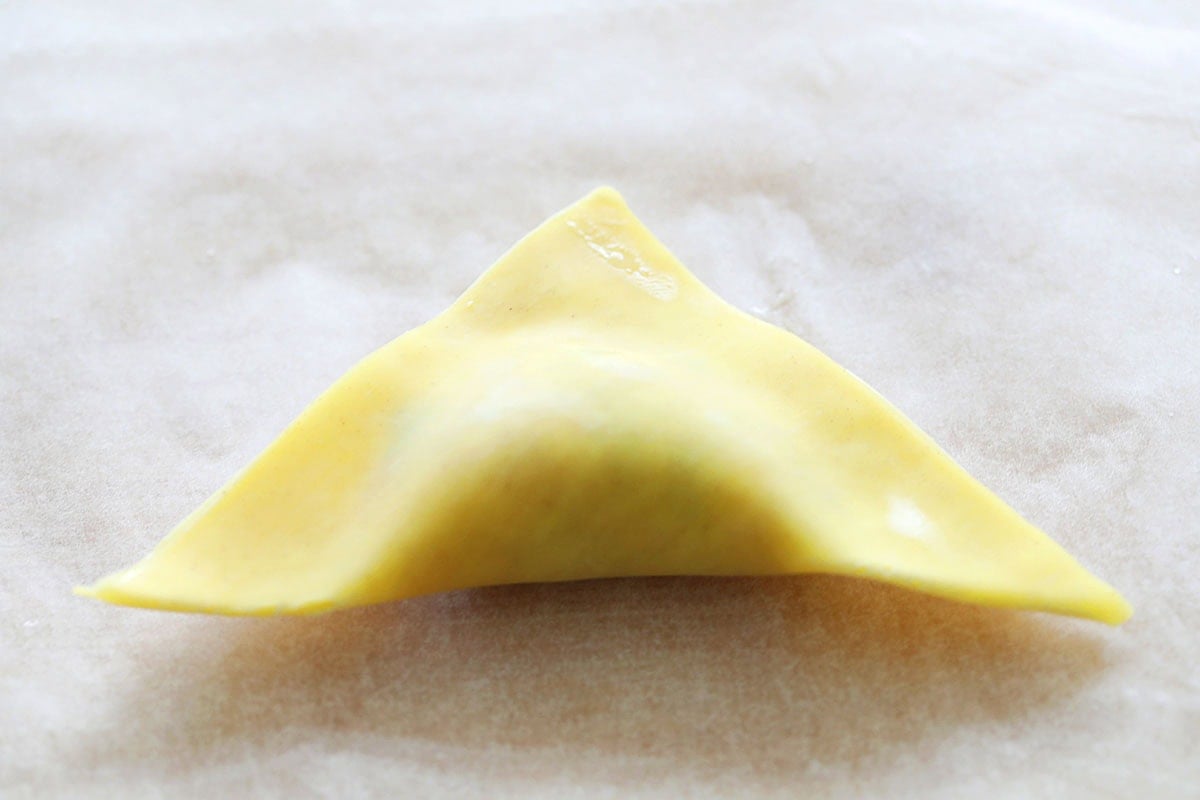 Triangle-shaped wonton on a parchment paper.