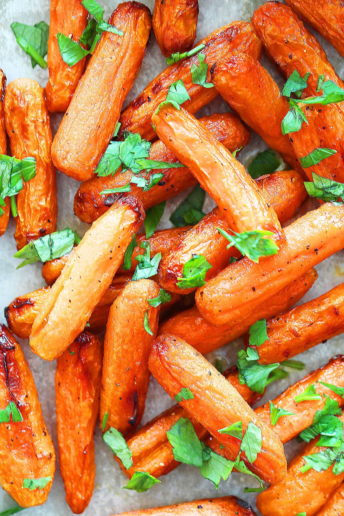 Roasted baby carrots with parsley on a tray, served as a side dish.