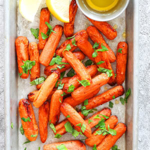 Air fryer honey butter carrots with honey butter drippings on tray.