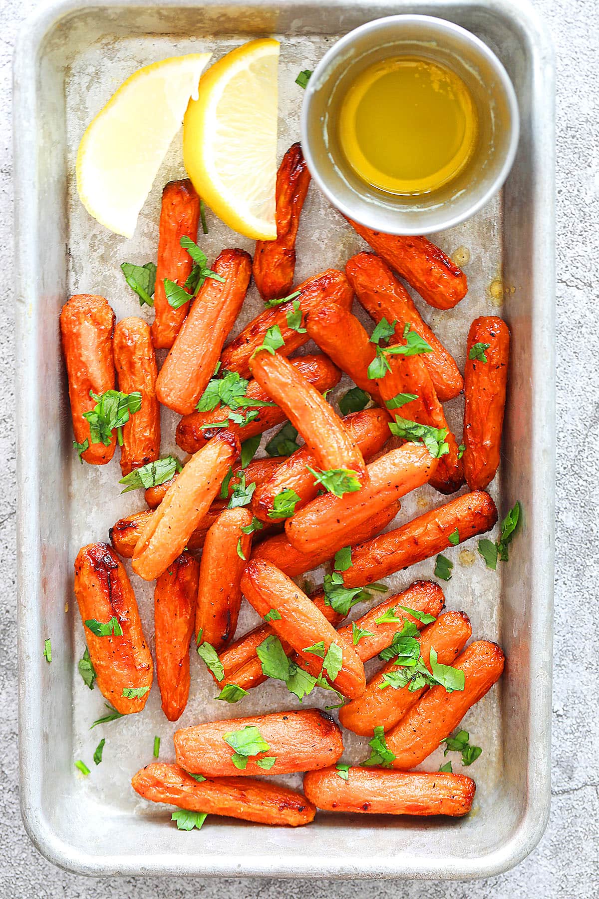 Air fryer honey butter carrots with honey butter drippings on tray.