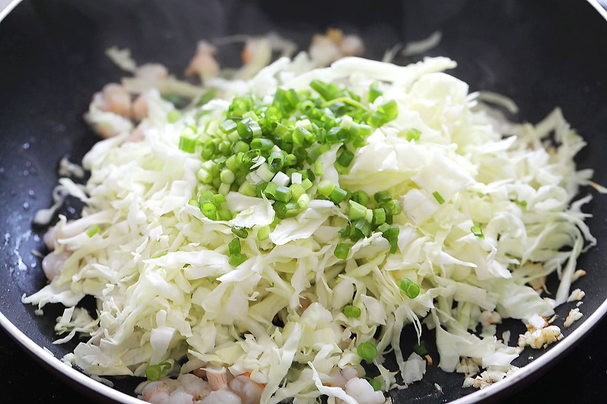 Shrimp, cabbage and scallion in a skillet.