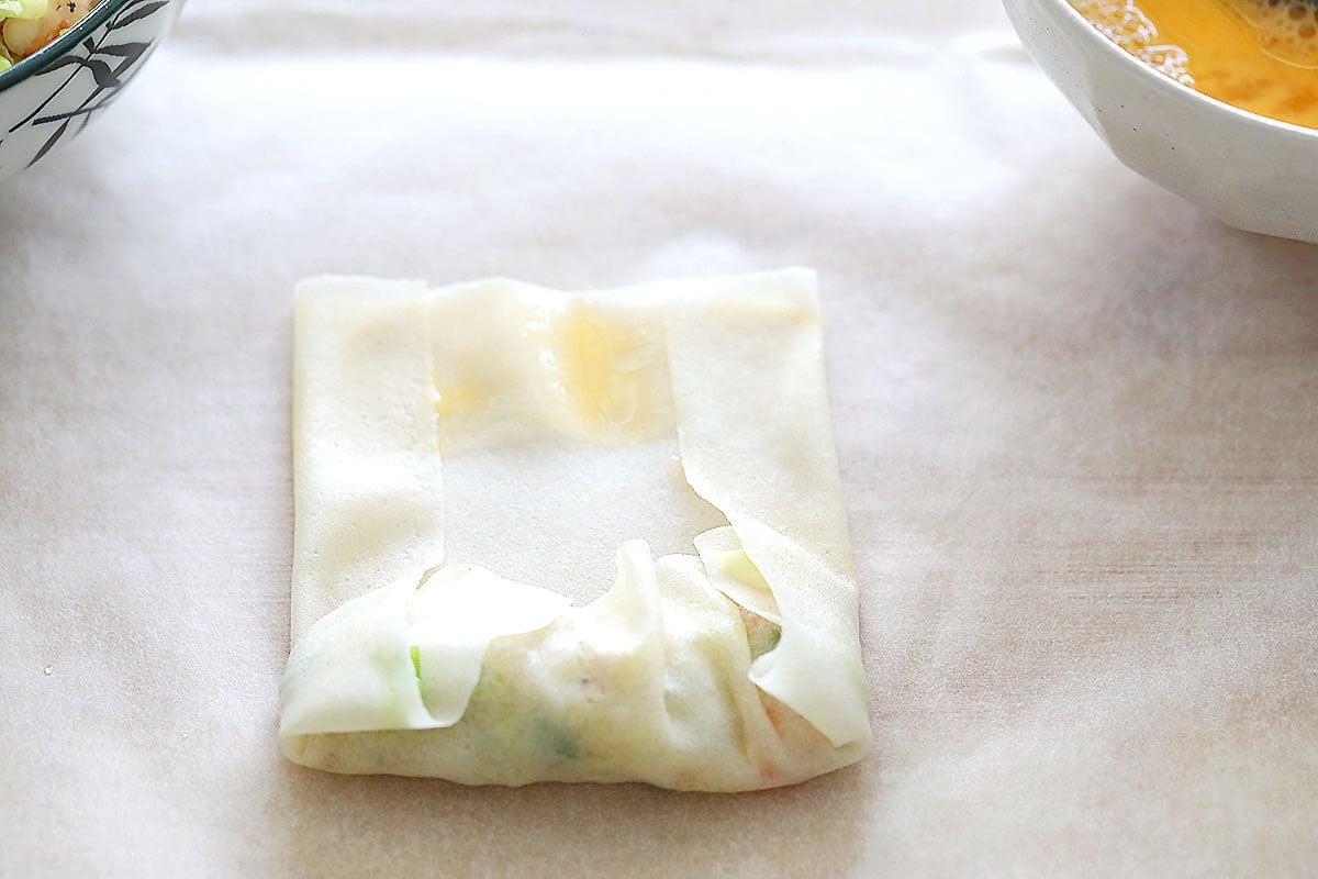 Spring roll wrapper with sides folded inward over the filling.