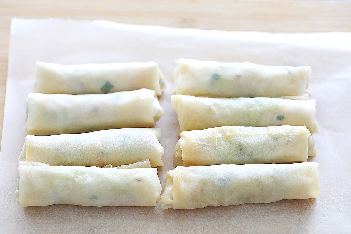 Uncooked spring rolls on parchment paper.
