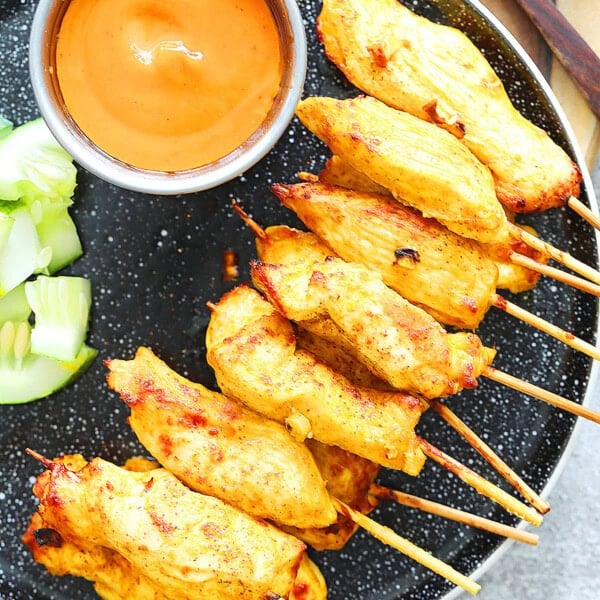 Juicy air fryer Thai chicken satay skewers with golden edges, served with fresh cucumber slices and homemade Thai peanut satay sauce.