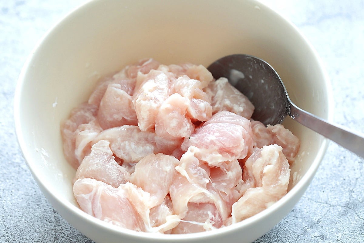 Chicken pieces coated in cornstarch in a bowl.