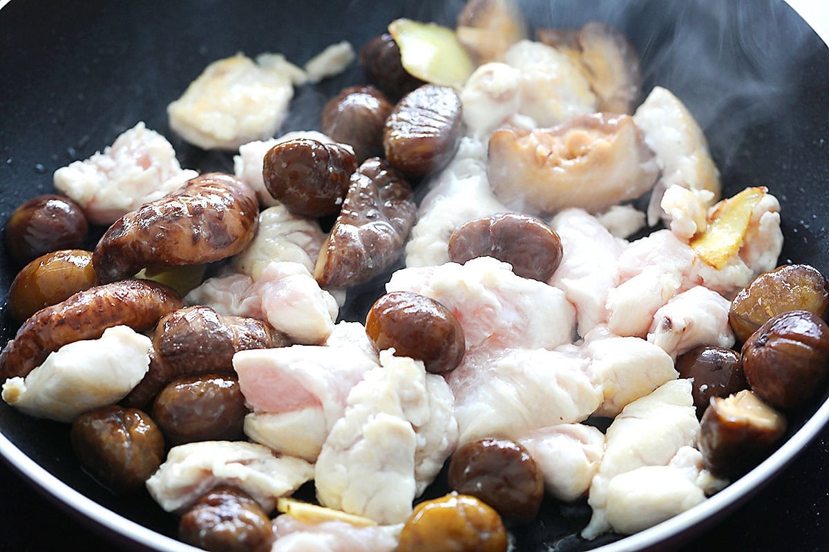 Chestnuts, shiitake mushrooms, ginger, and chicken in a skillet.