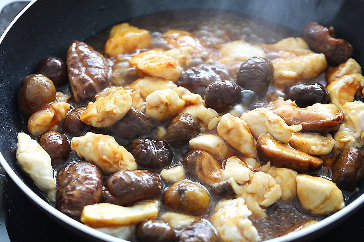 Chicken, chestnuts, and shiitake mushrooms simmering in brown sauce.