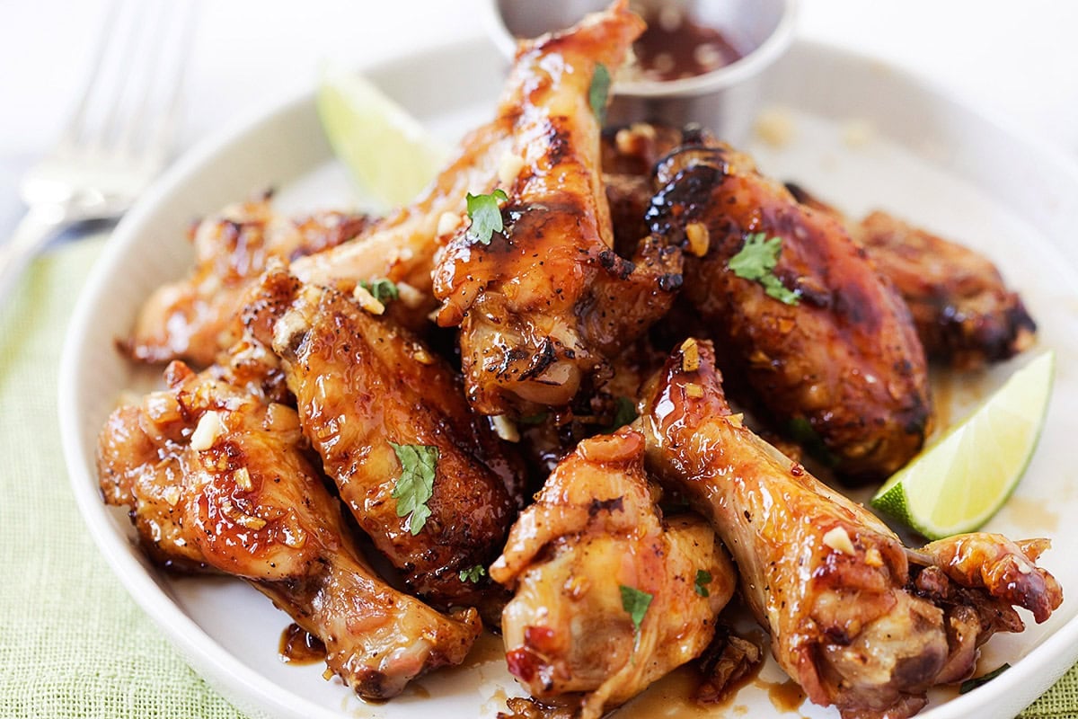 Baked Vietnamese chicken wings served on a plate with lime wedges.