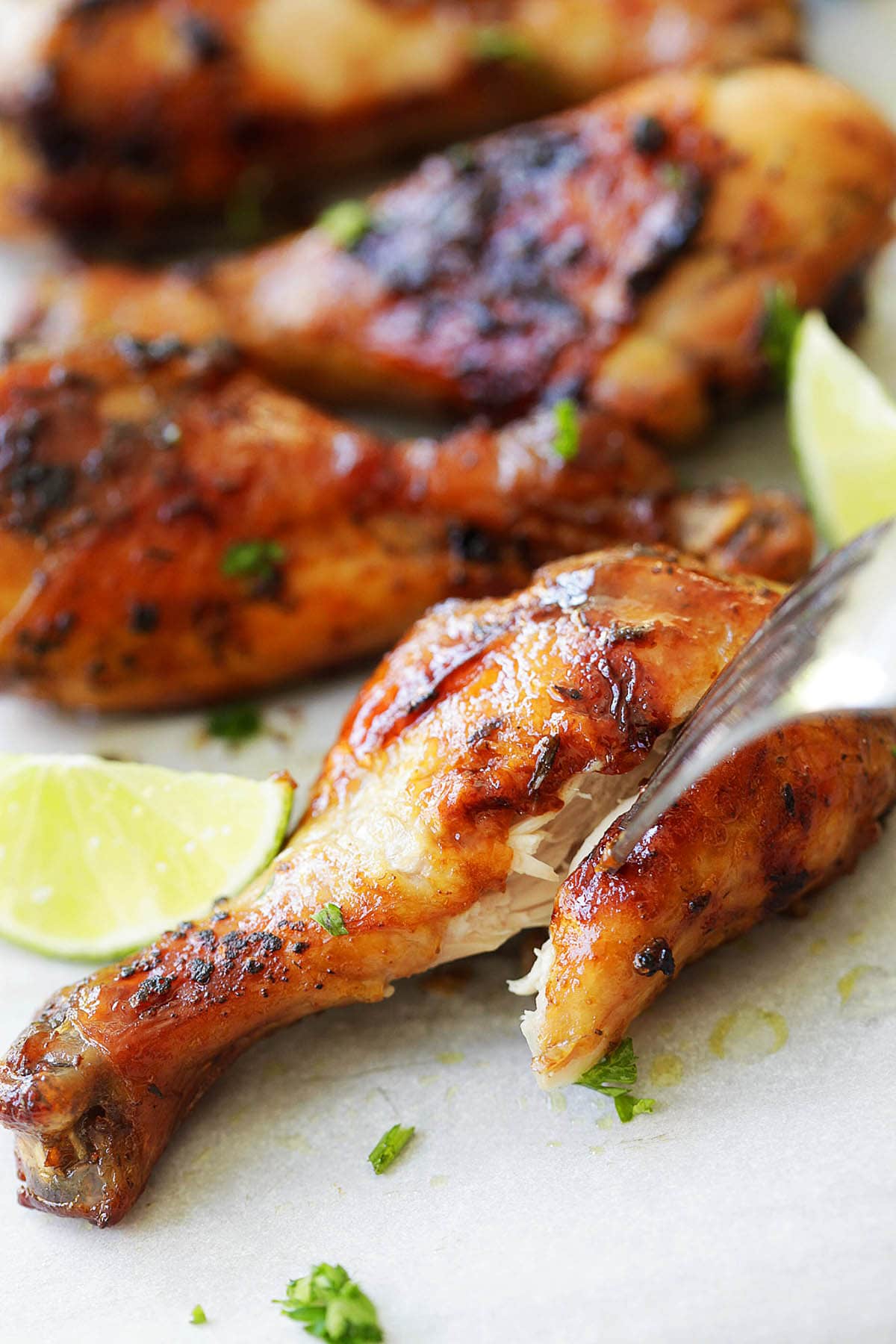 Juicy grilled jerk chicken leg pierced with a fork.