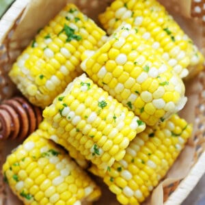 Easy honey butter corn on the cob arranged in a wooden basket.
