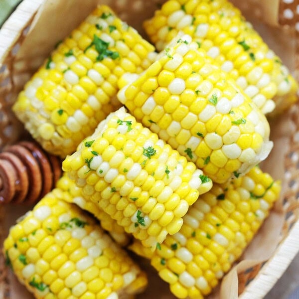 Easy honey butter corn on the cob arranged in a wooden basket.