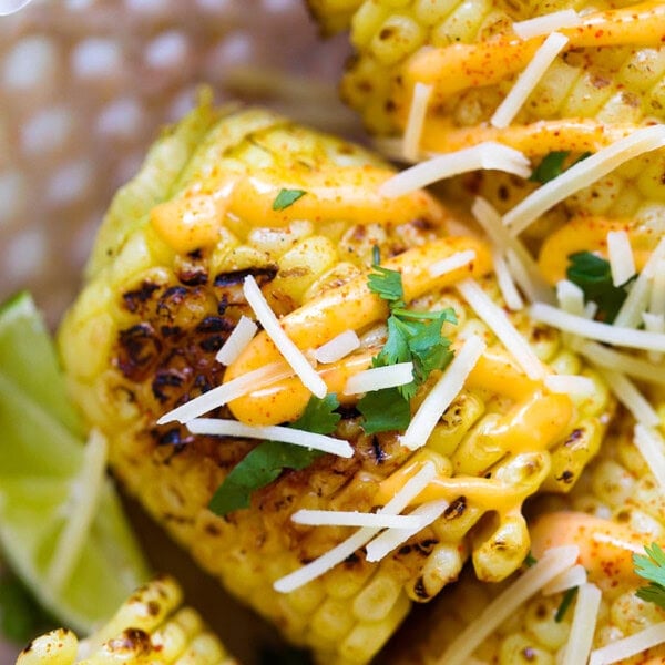 Easy grilled corn on the cob loaded with spicy mayo, shredded Parmesan, and chopped cilantro.