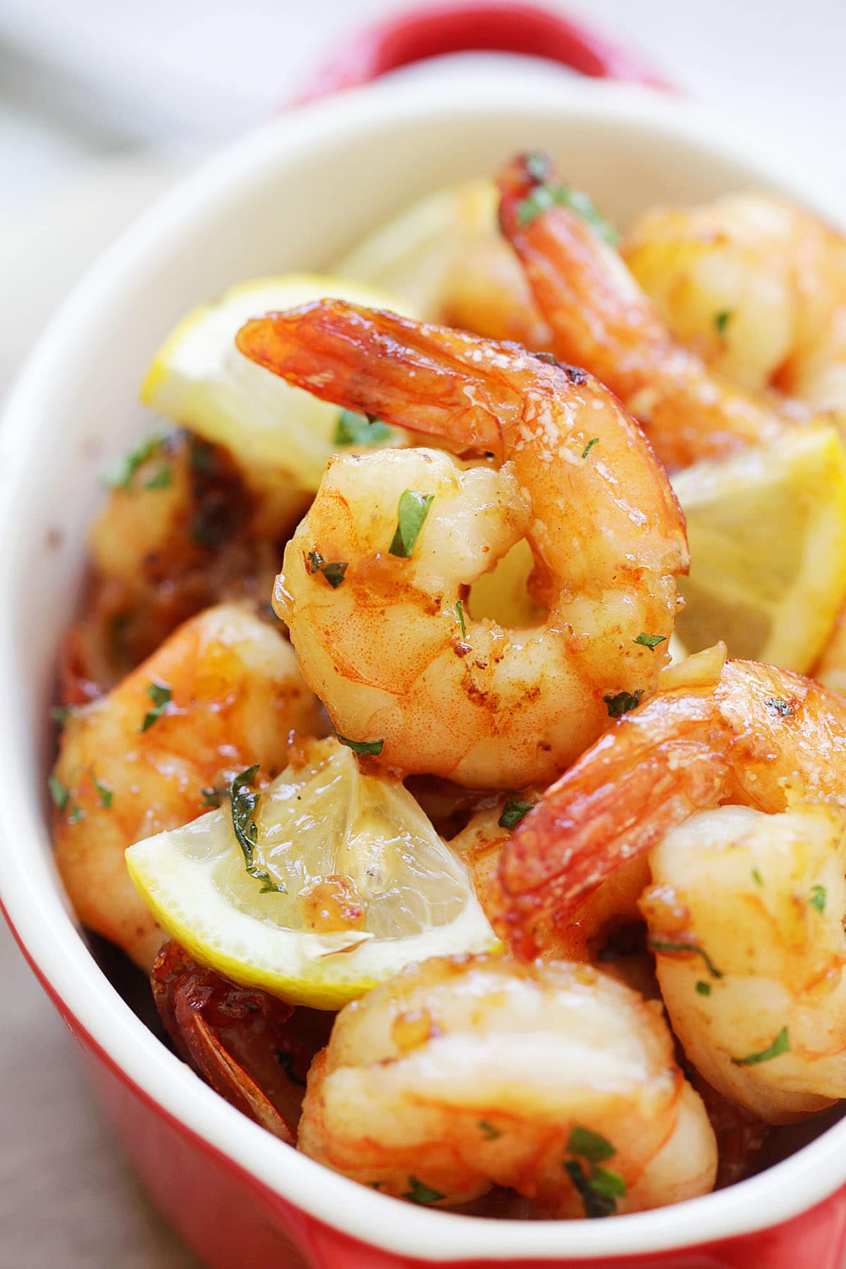 Oven baked garlic herb shrimp topped with parsley and lemon wedges.