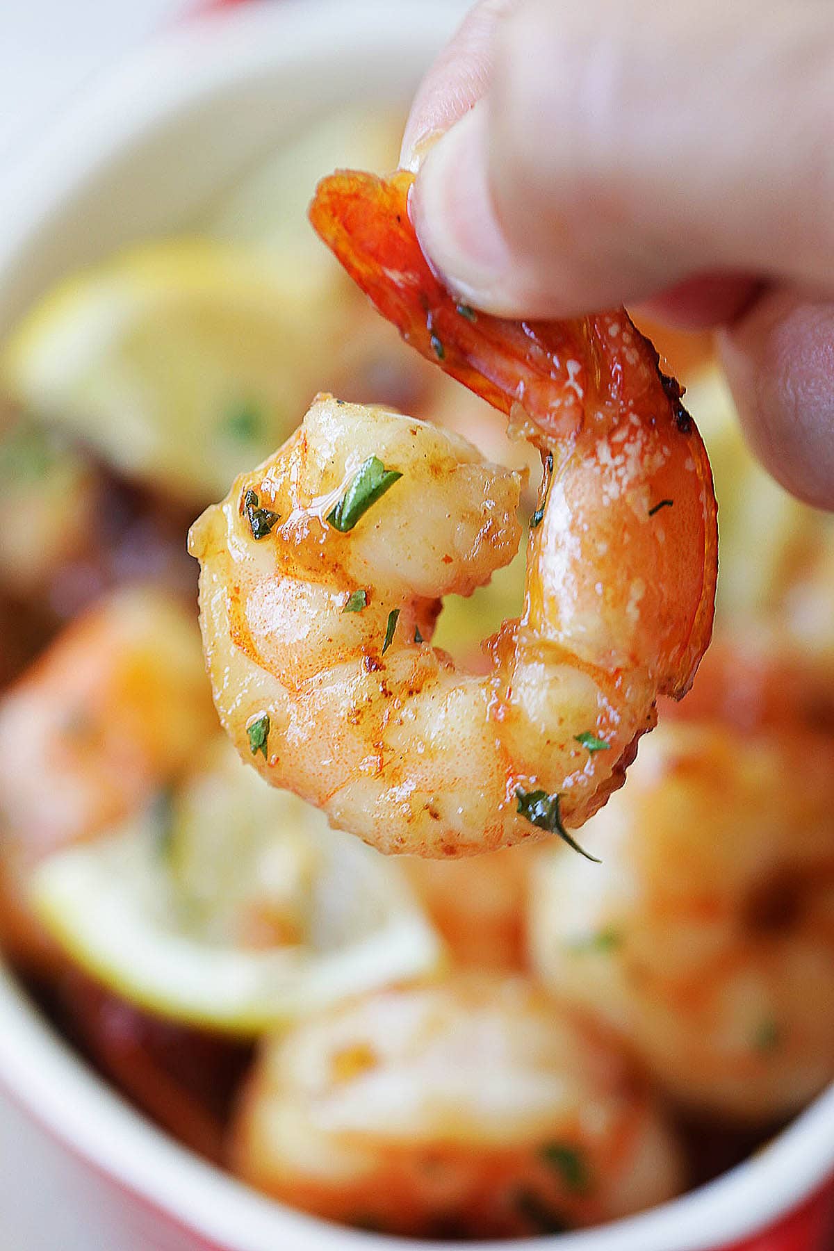 Garlic herb oven baked shrimp appetizer being picked up with fingers.