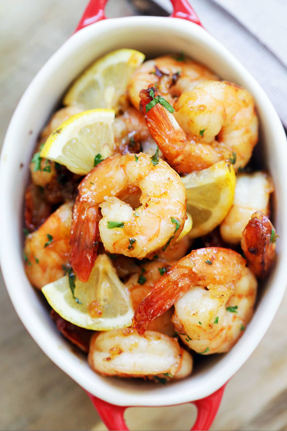 Garlic herb oven baked shrimp served with lemon wedges.