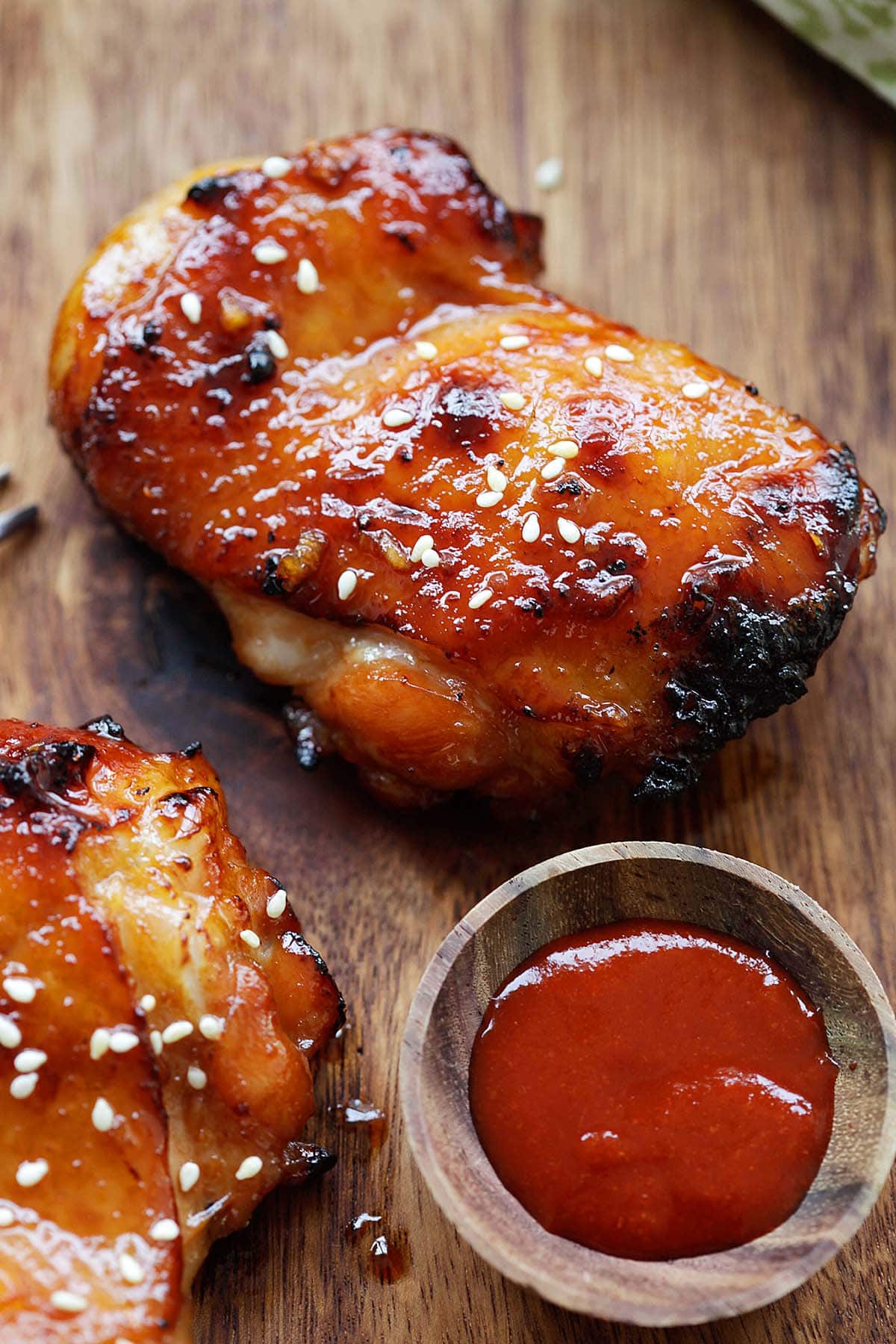 Boneless Sriracha chicken thighs with a glossy, sticky-sweet honey sauce, served on a chopping board.