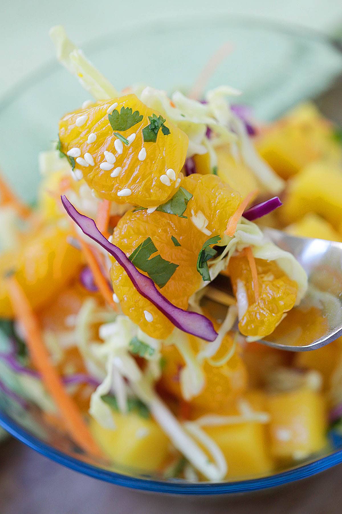 Summer fruit salad recipe with mango and mandarin orange on a fork.