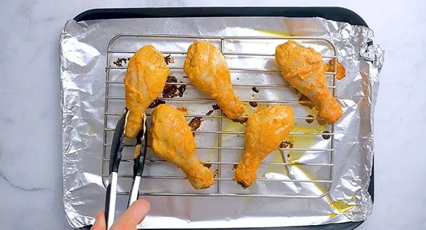Marinated tandoori chicken on a wire rack.
