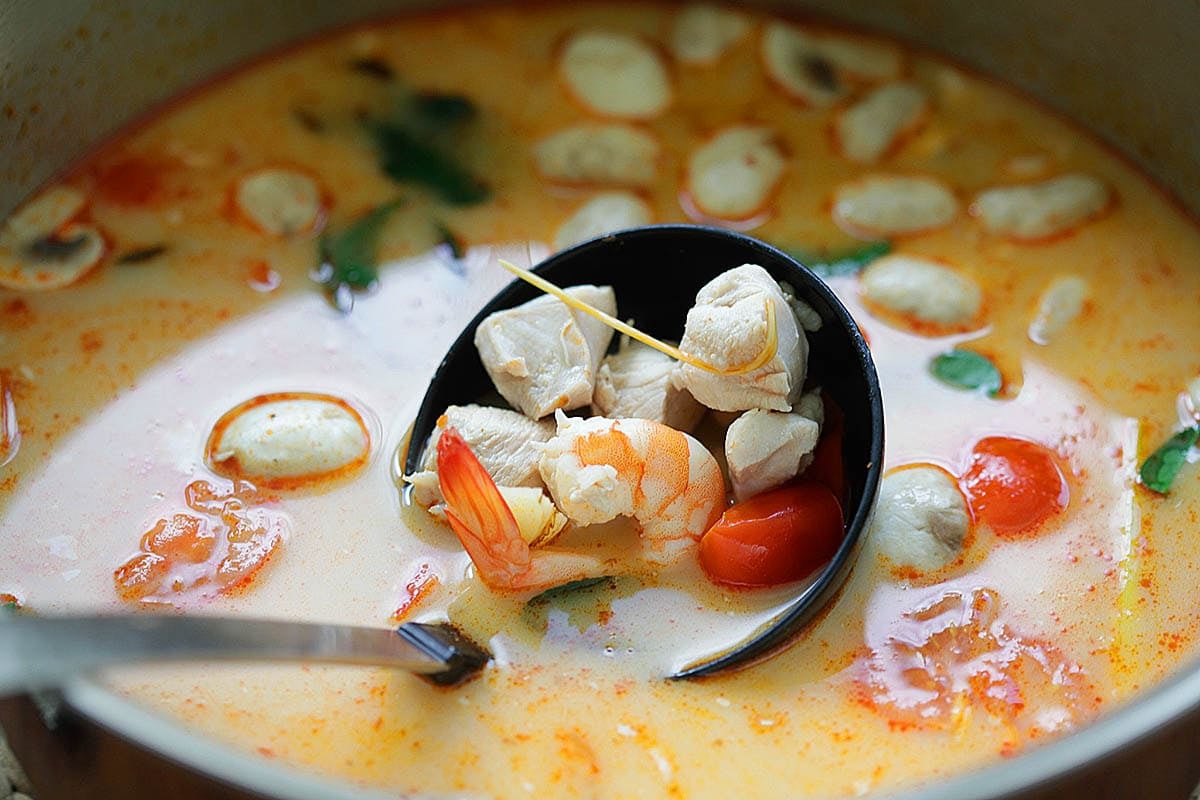 Ladle of spicy Thai coconut soup with shrimp, chicken, and chilies.