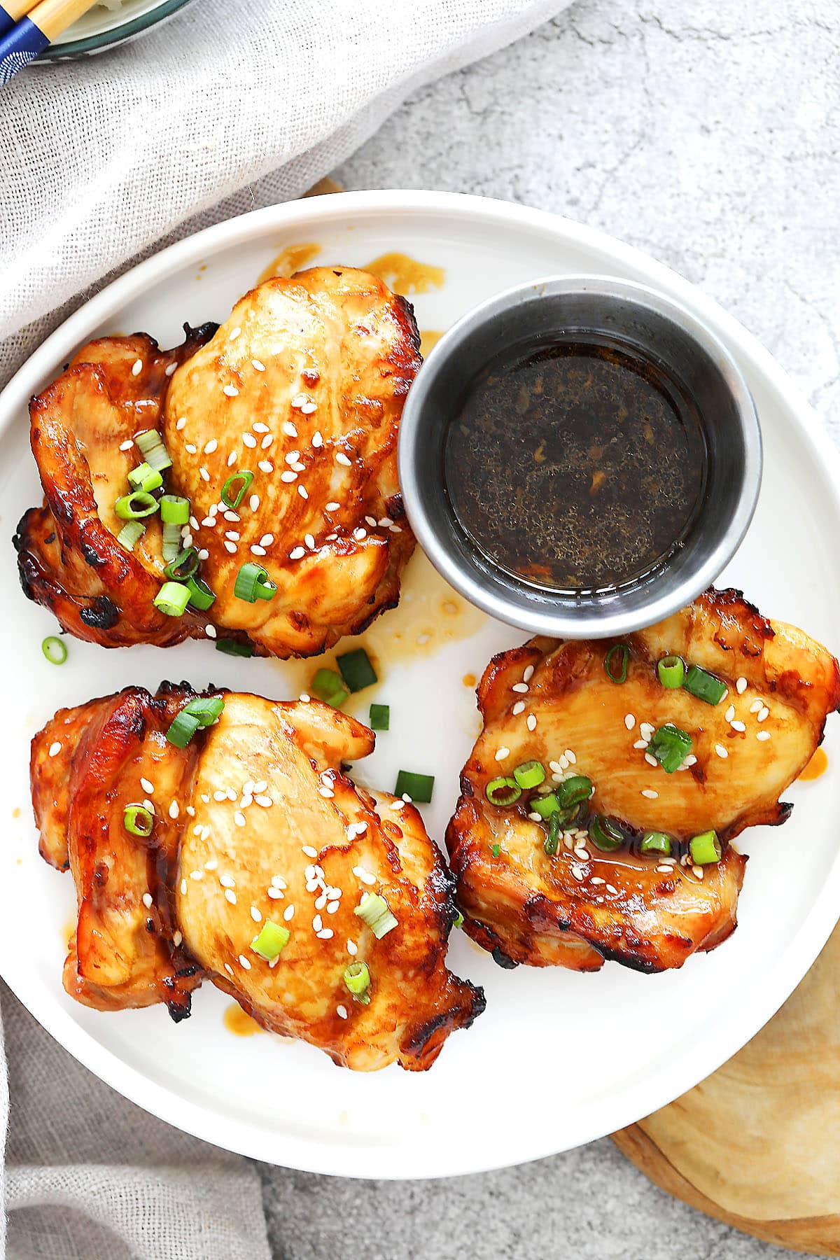 Air fryer teriyaki chicken recipe made with juicy boneless chicken thighs, garnished with sesame seeds and scallions on a plate.