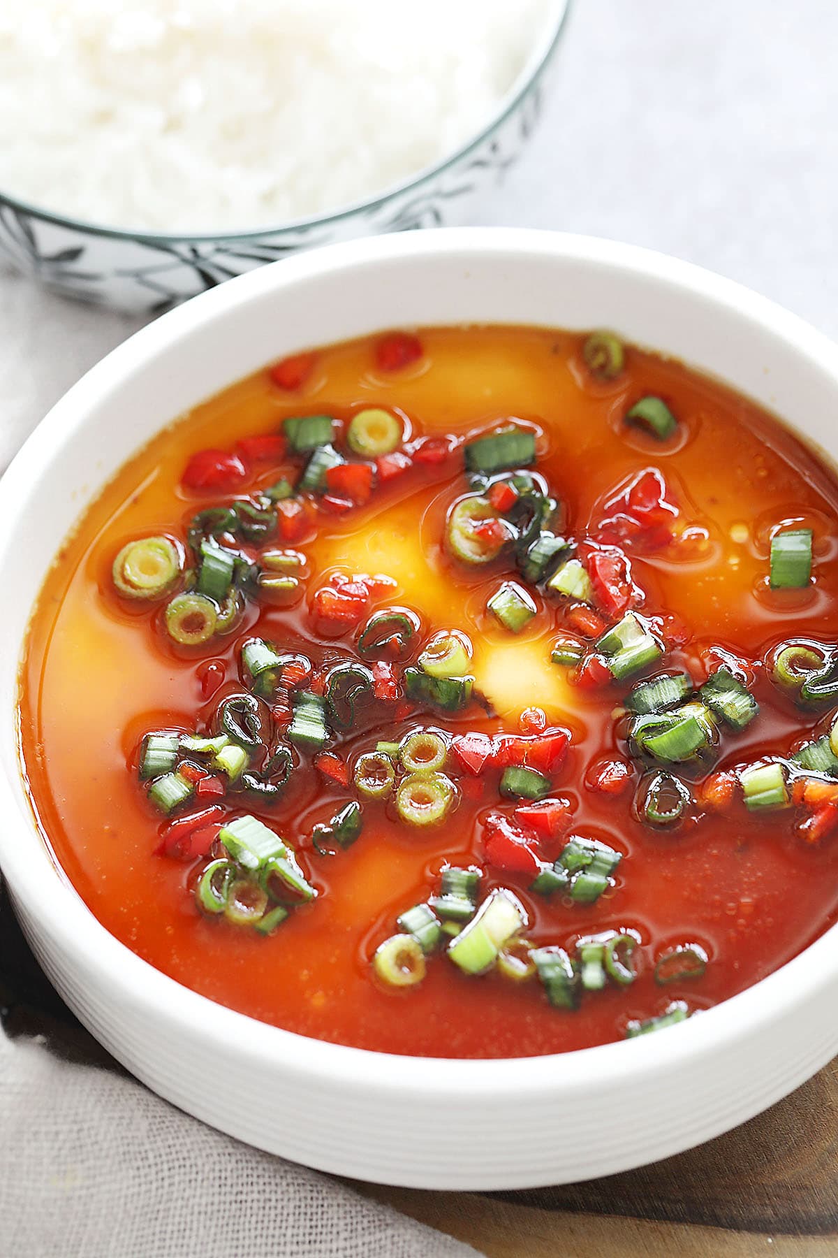 Homemade Chinese steamed egg custard with soy sauce drizzle, fresh scallion, and red chili garnish.
