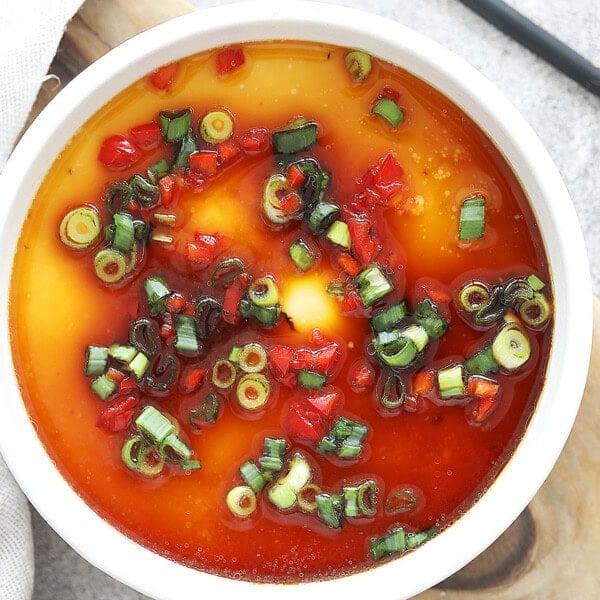 Chinese steamed eggs garnished with chopped scallions and red chili.
