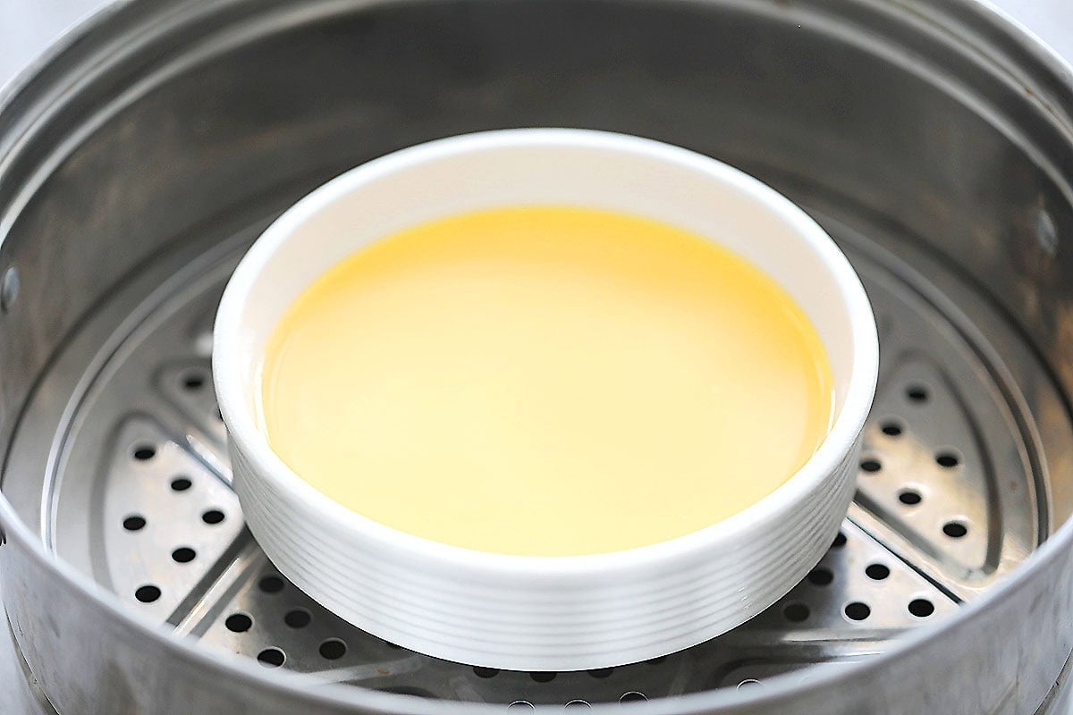 Egg mixture in a bowl set inside a steamer.