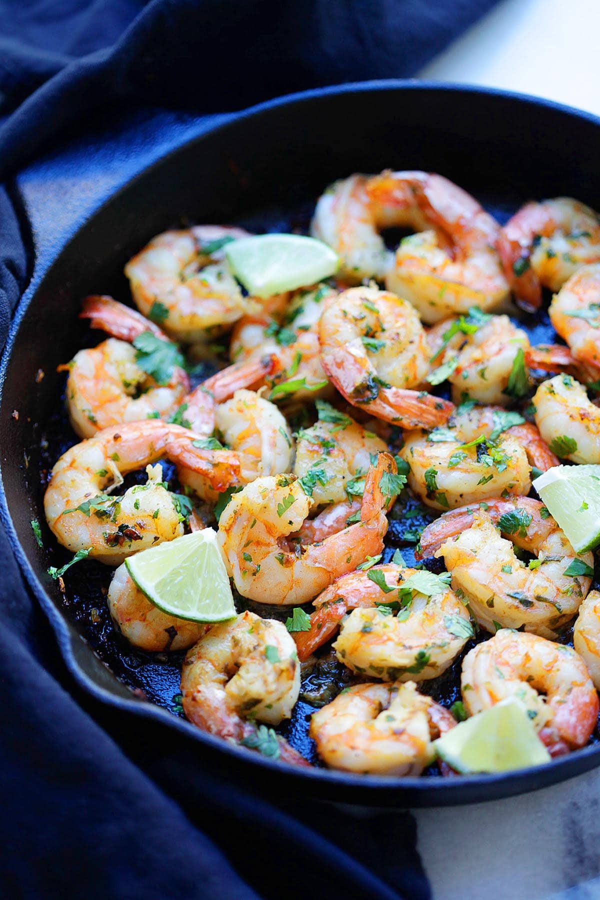 Cast-iron skillet filled with golden seared cilantro and lime shrimp tossed in garlic butter.