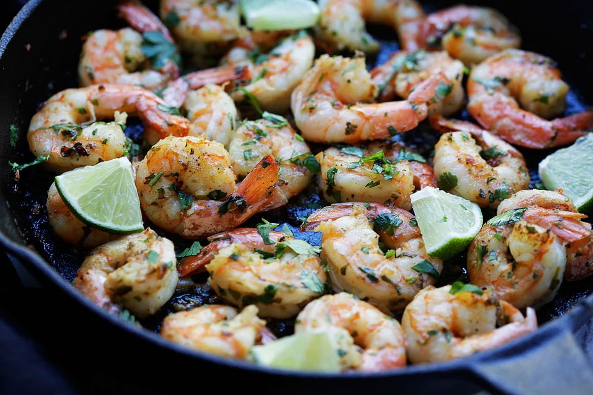 Juicy cilantro lime shrimp sizzling in a cast-iron skillet with garlic butter and fresh herbs.