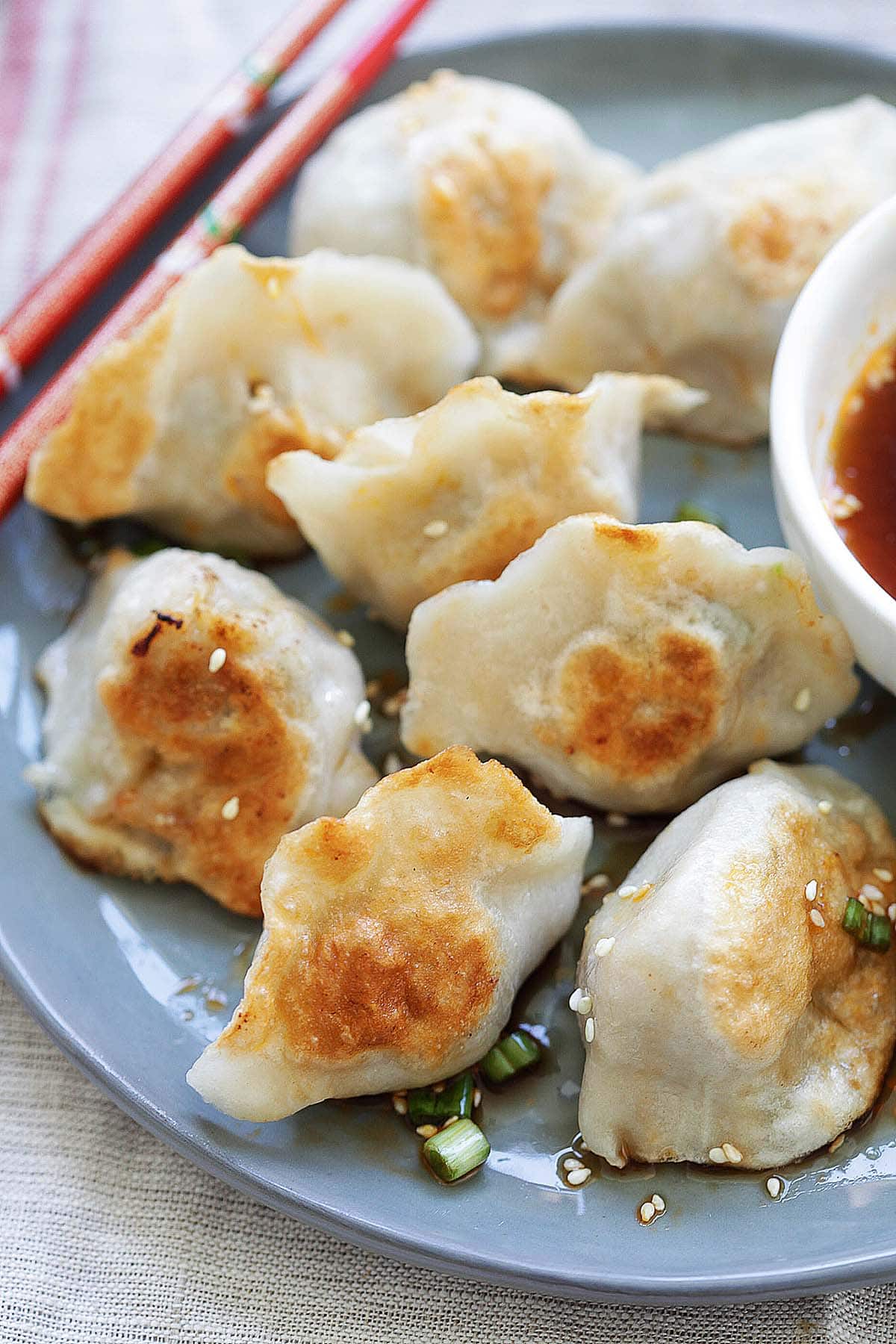 Crispy pan fried dumplings served on plate with dipping sauce.