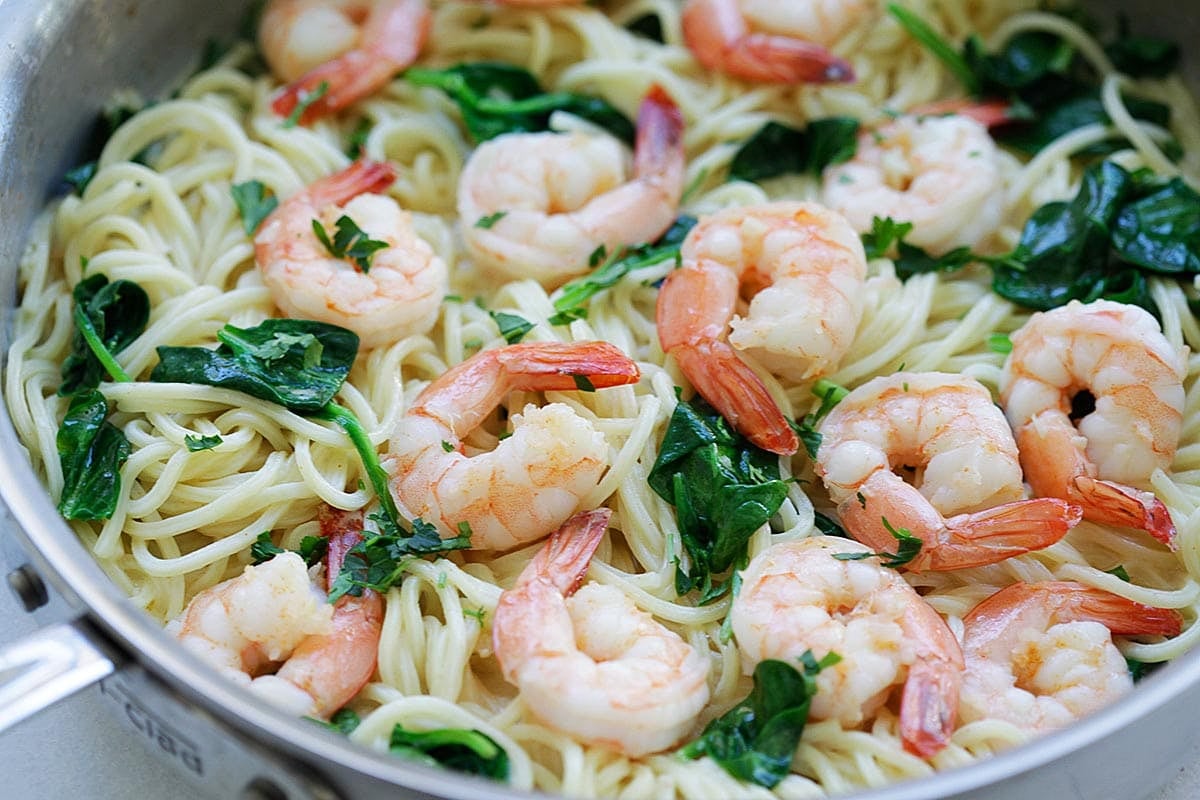 Garlic butter shrimp spinach pasta in a skillet.