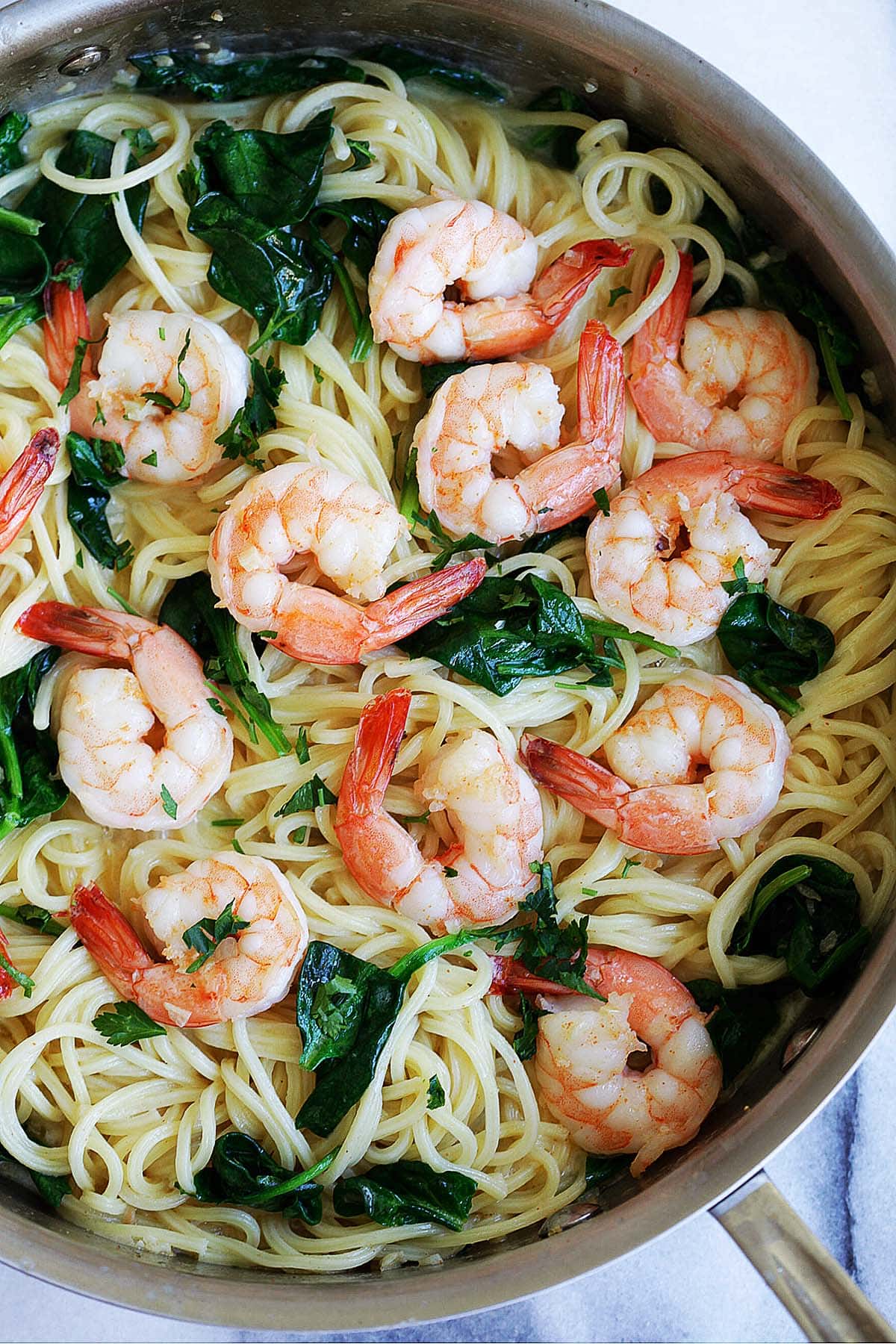 Healthy shrimp and spinach pasta in a skillet.