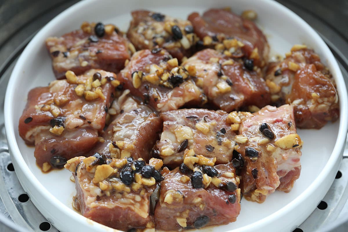 Marinated pork ribs in a steamer-safe dish inside a steamer.