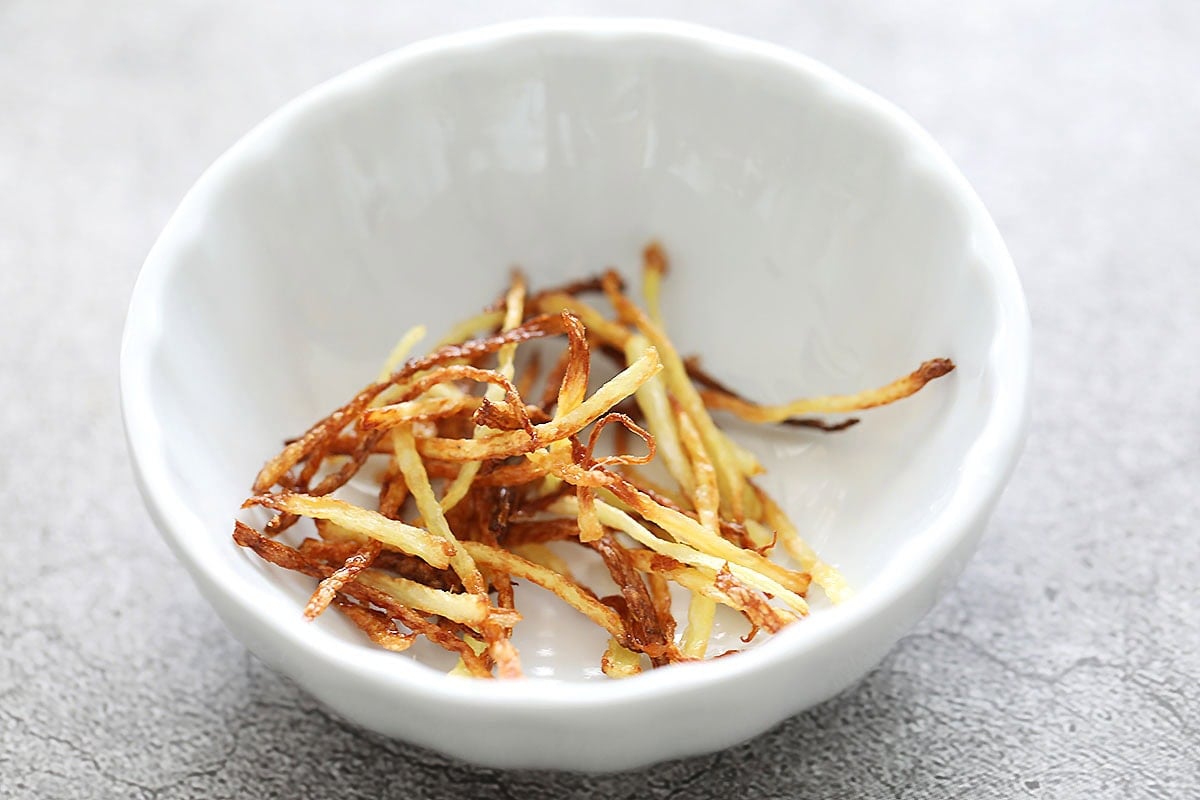 Fried ginger strips in a small bowl.