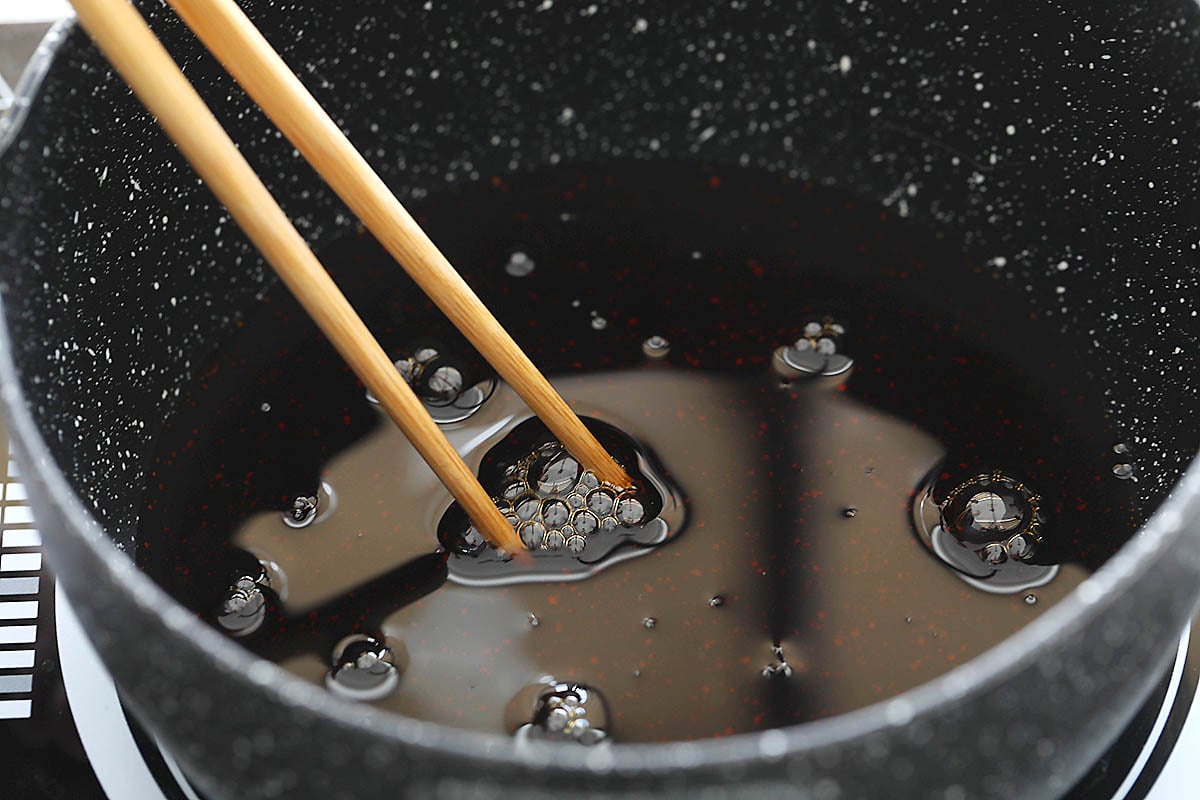 Teriyaki sauce being stirred with chopsticks.