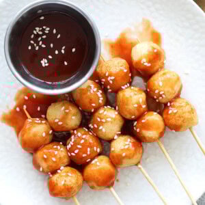Easy sweet and sour fish balls recipe on a plate with dipping sauce on the side.