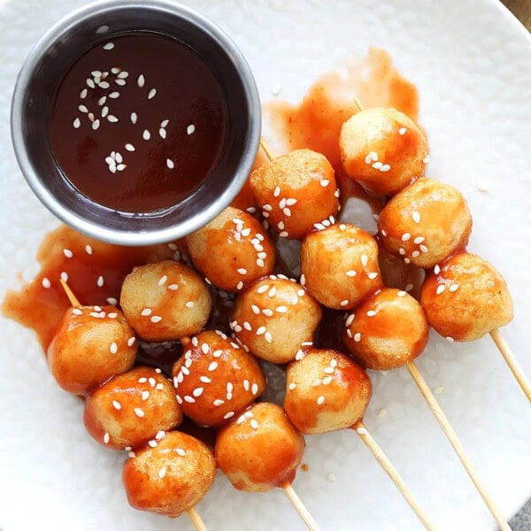 Easy sweet and sour fish balls recipe on a plate with dipping sauce on the side.