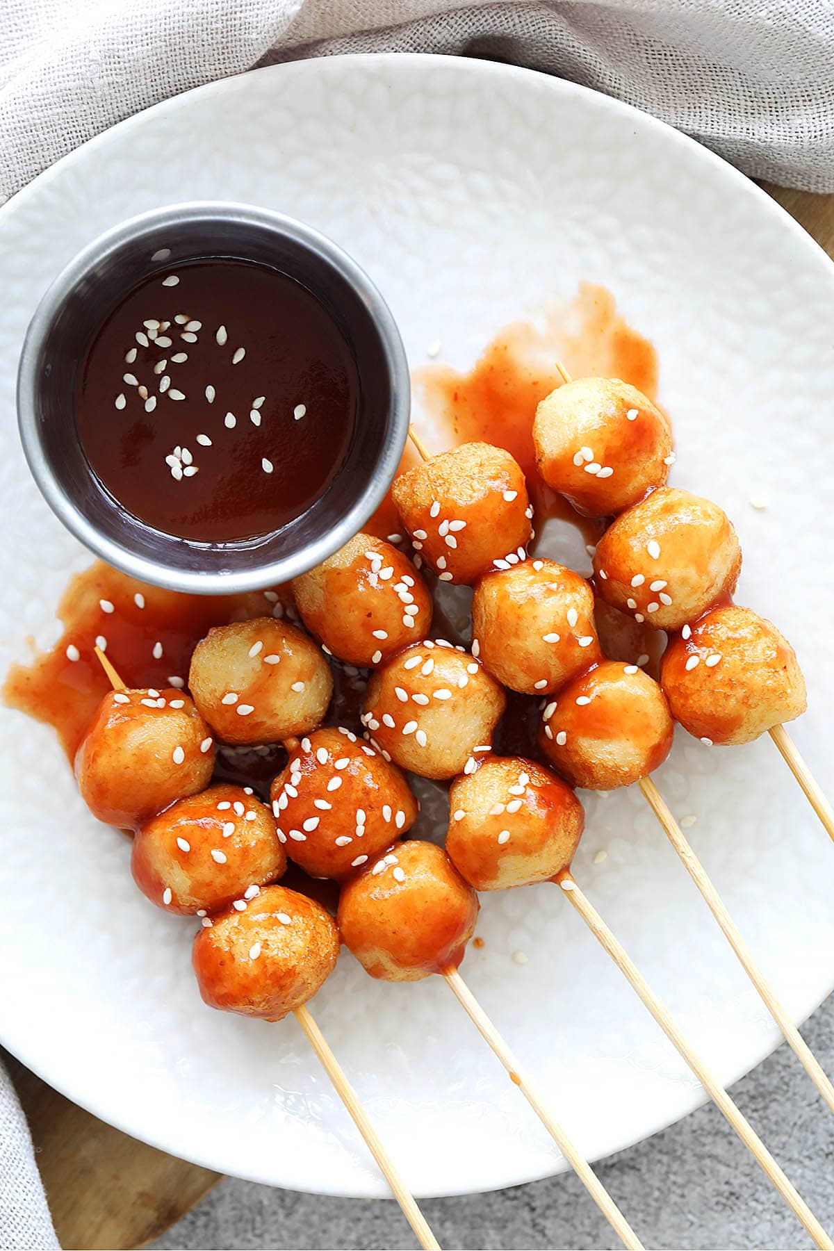 Easy sweet and sour fish balls recipe on a plate with dipping sauce on the side.