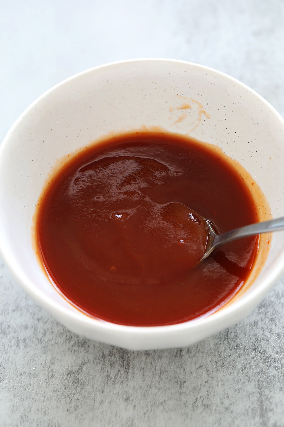 Bowl of homemade sweet and sour sauce with a spoon resting inside.