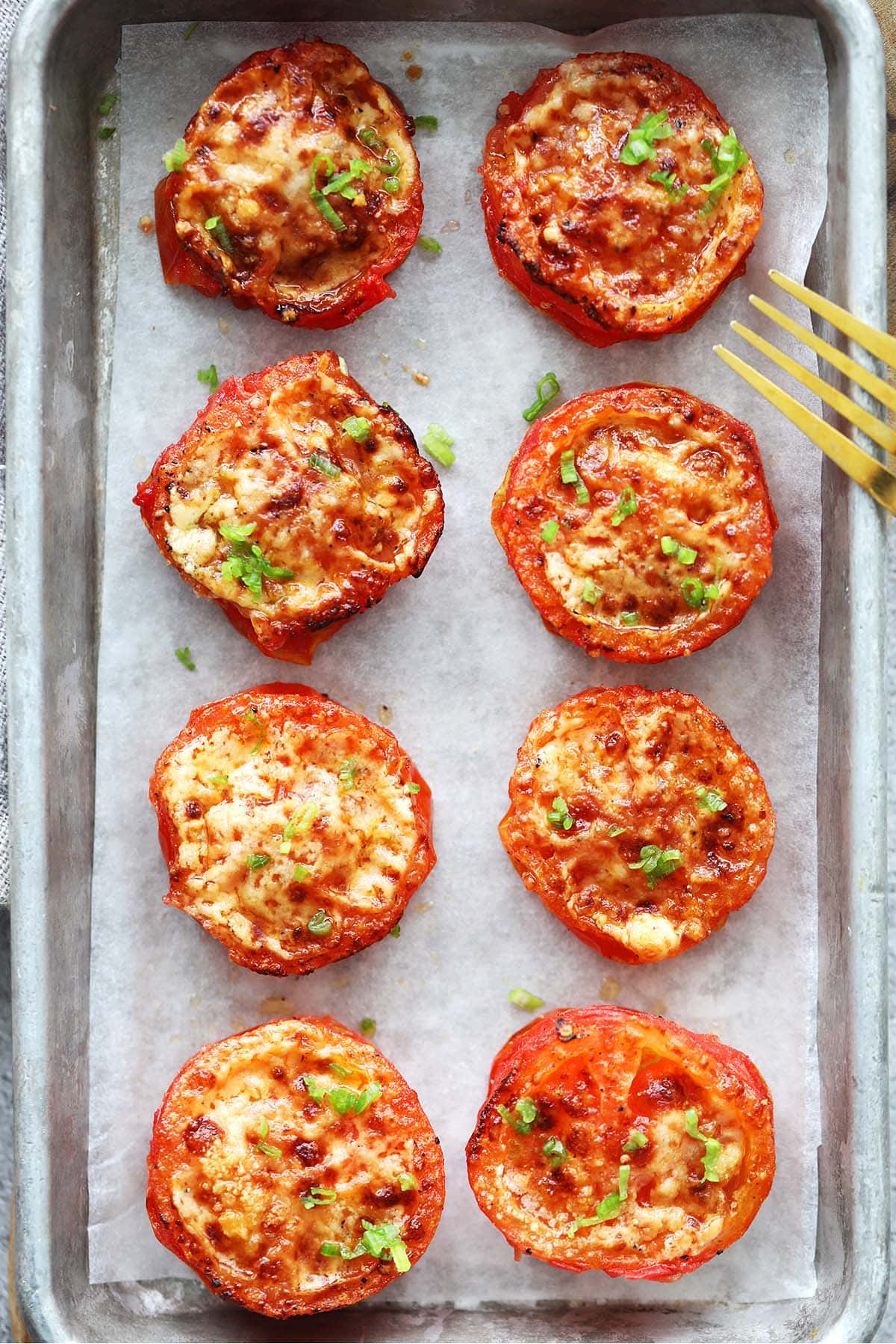 Perfectly roasted air fryer tomatoes with Parmesan cheese and chive garnish.