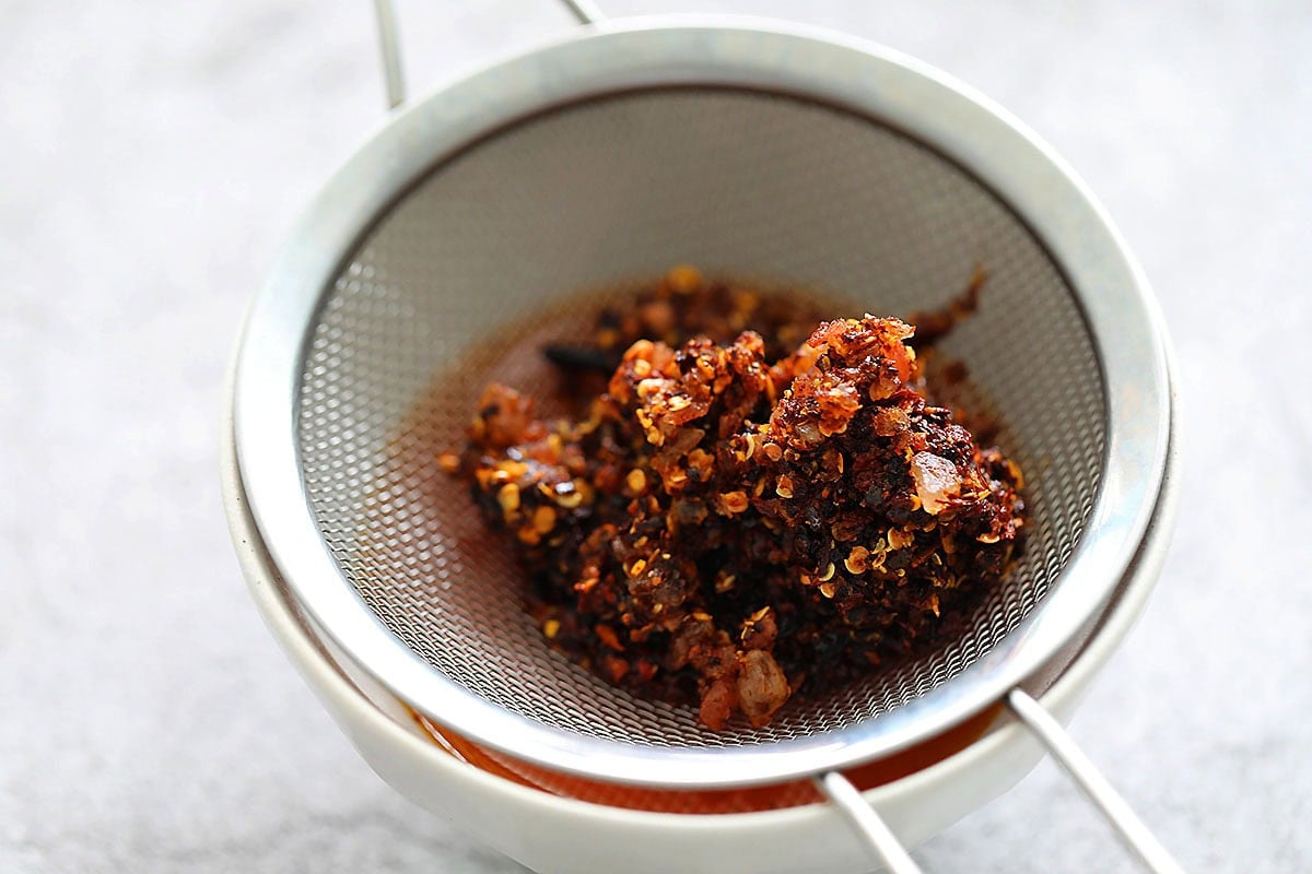 Chili flakes and cloves in a stainer.