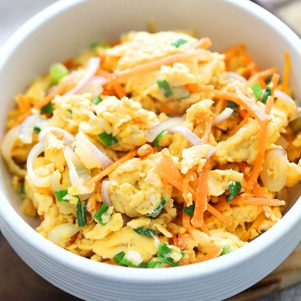 Chinese scrambled eggs with carrots, onions, and scallions served in a bowl.