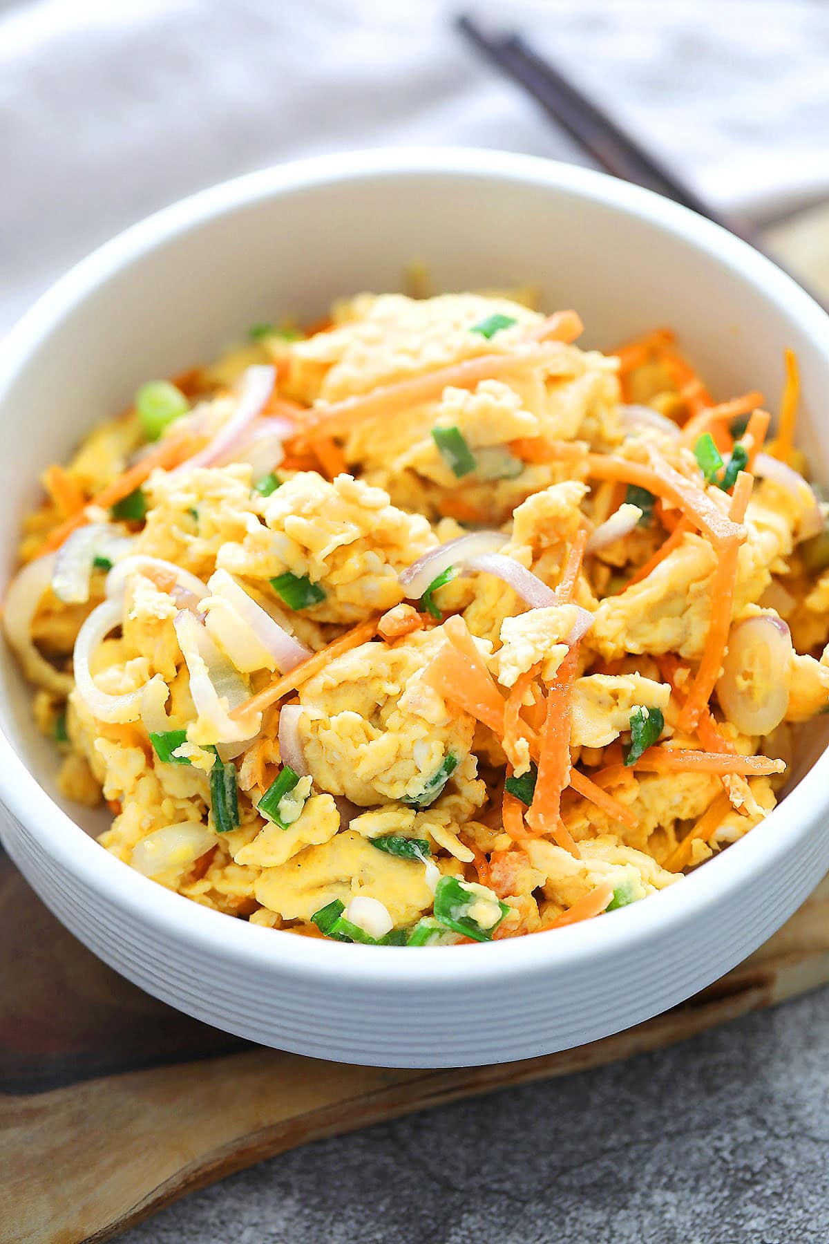 Chinese scrambled eggs with carrots, onions, and scallions served in a bowl.