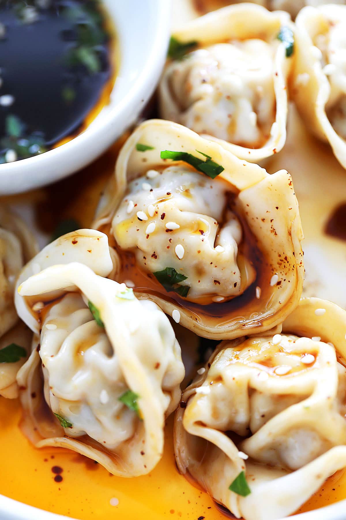 Szechuan red oil wontons garnished with sesame seeds.