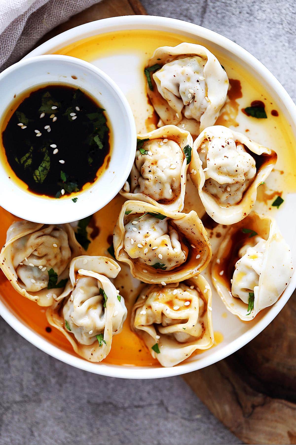 Sichuan spicy red oil wontons served with dumpling dipping sauce.