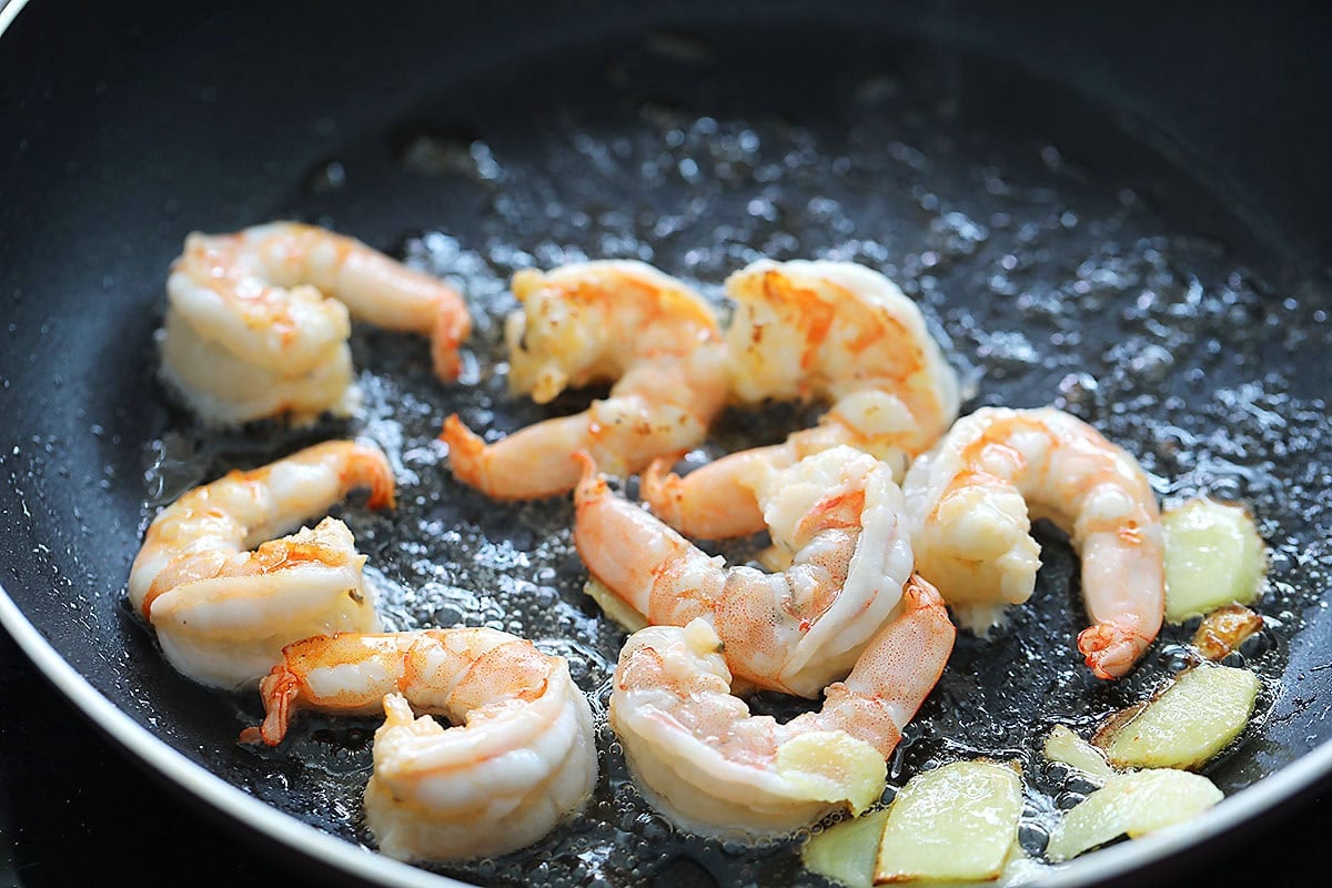 Cooked shrimp and ginger in a pan.
