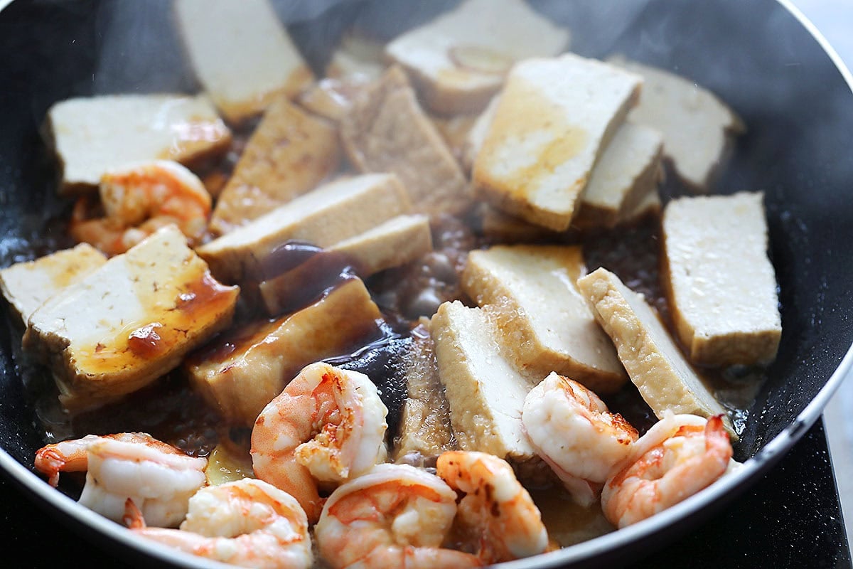 Savory Chinese sauce, fried tofu and shrimp in a pan.