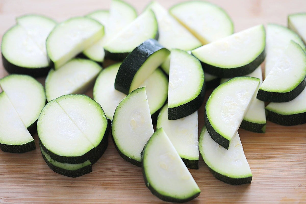 Half-moon zucchini slices on a chopping board.