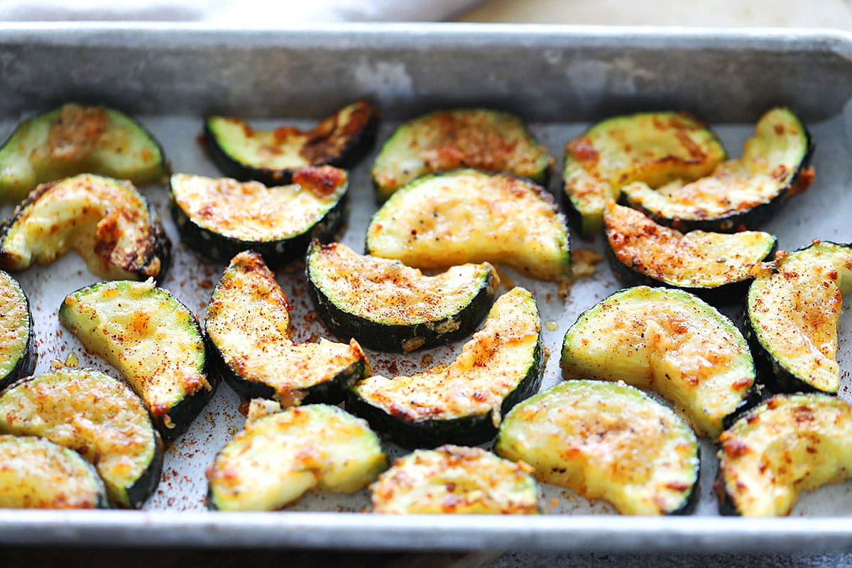 Golden, crispy air fryer zucchini topped with paprika, served in a tray.