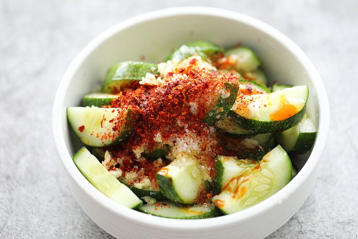 Cucumber slices with seasonings for Asian cucumber salad in a bowl.
